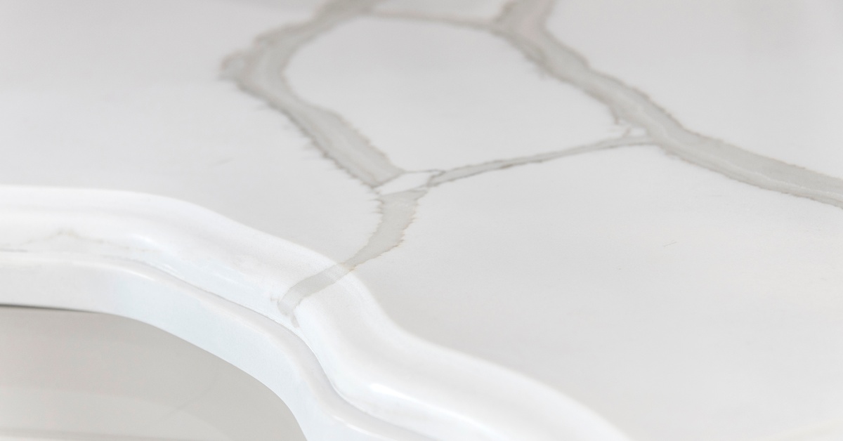 A close-up of marbled white quartz countertops. The ogee edge profile is very unique and adds character.
