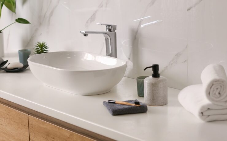 A bathroom vanity with a porcelain sink resting on top of white counters. Towels, a toothbrush, and soap rest on the counter too.