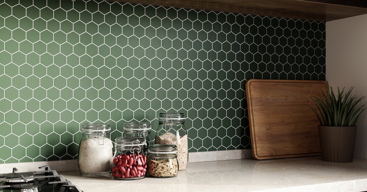 Glass jars, a plant, and a cutting board rest on a white countertop. There is a green honeycomb-patterned backsplash.